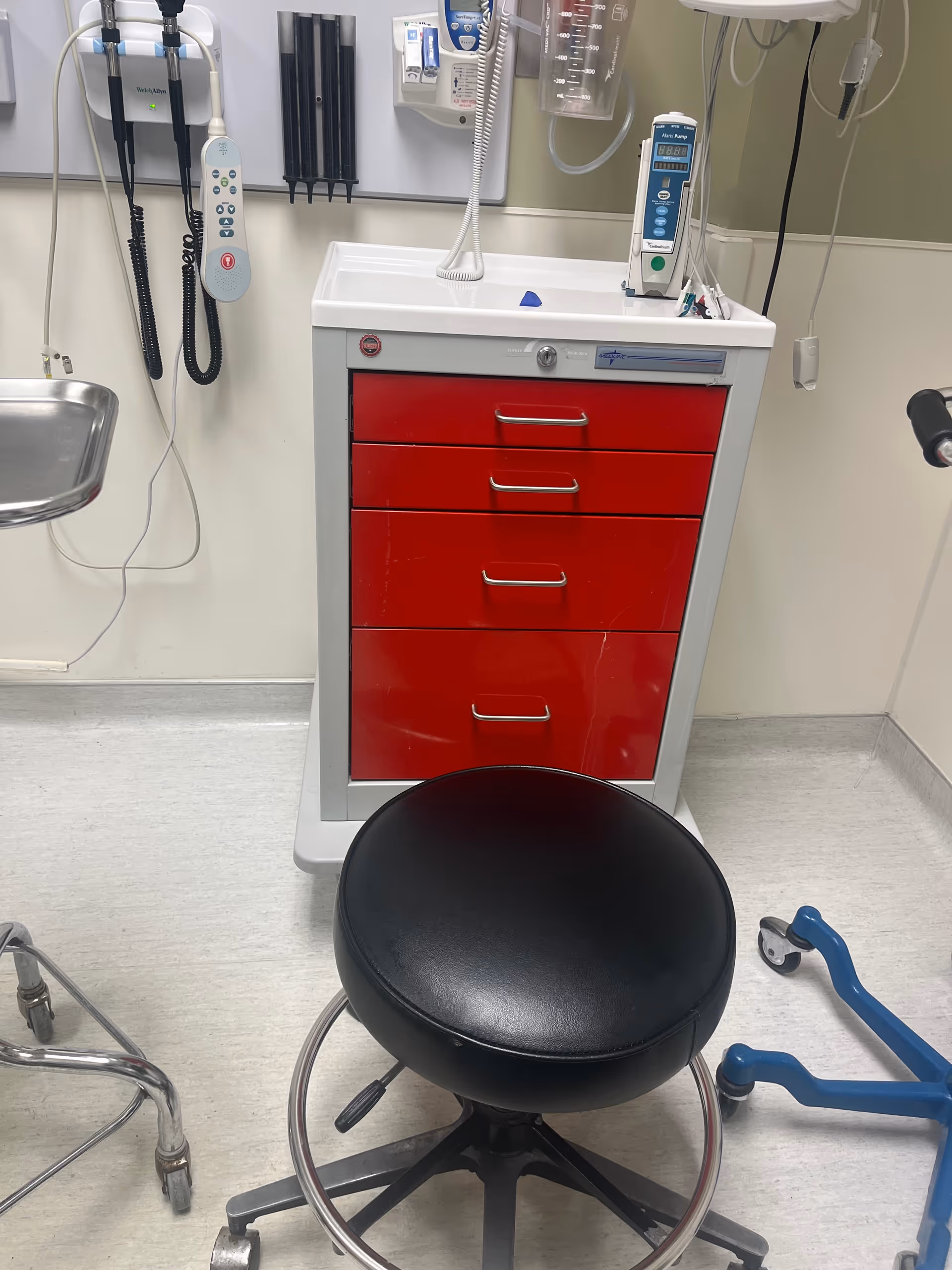 Medical examination room featuring a red-drawer cabinet and medical equipment.