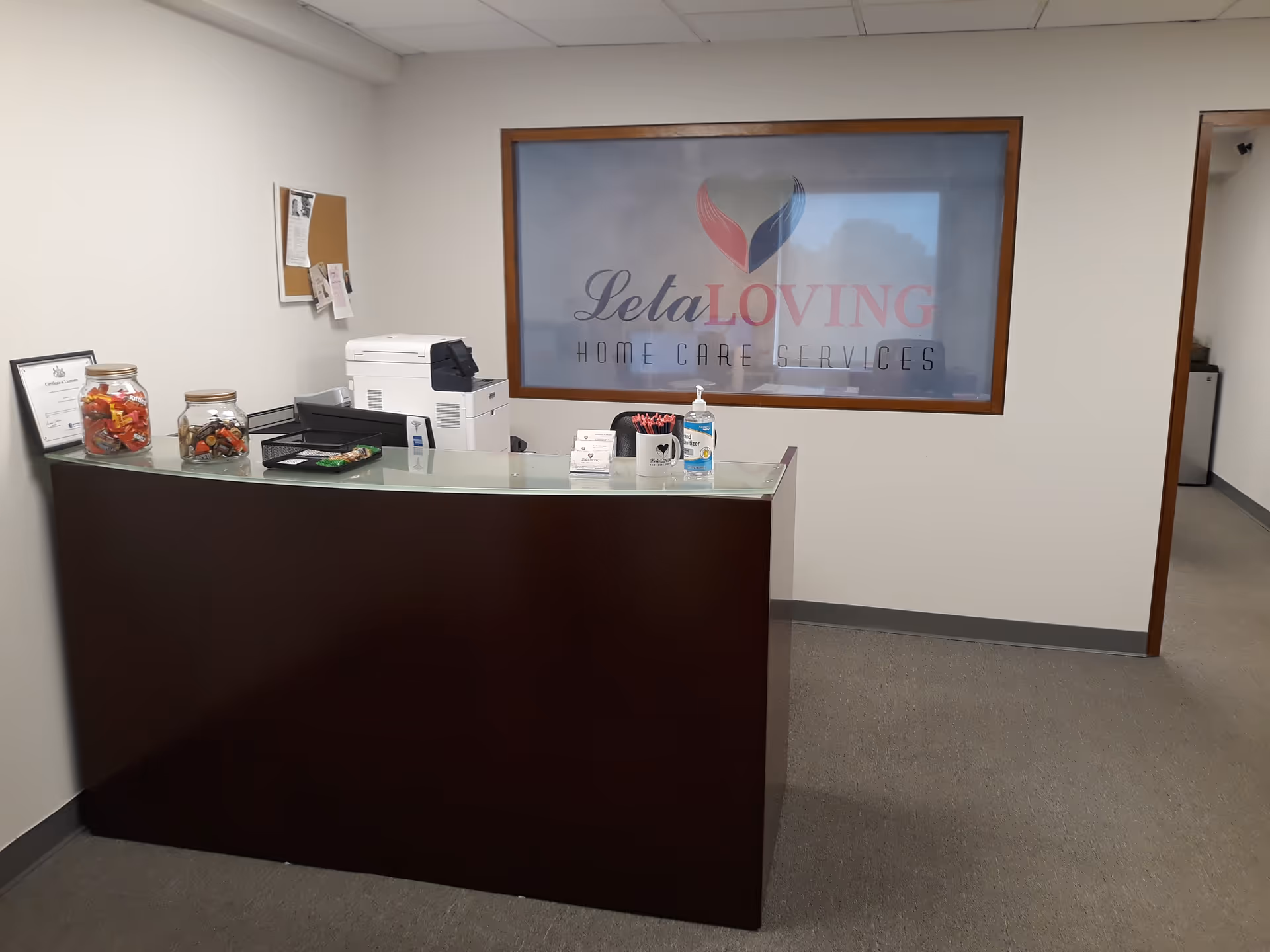 Reception desk with candy jars and Leta Loving Home Care Services sign in lobby.