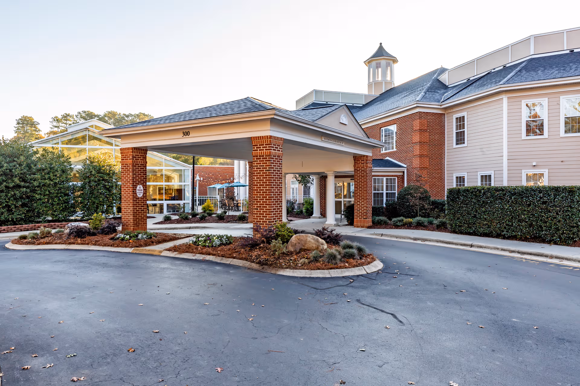 Senior living facility entrance with brick pillars, glass lobby, and circular driveway.