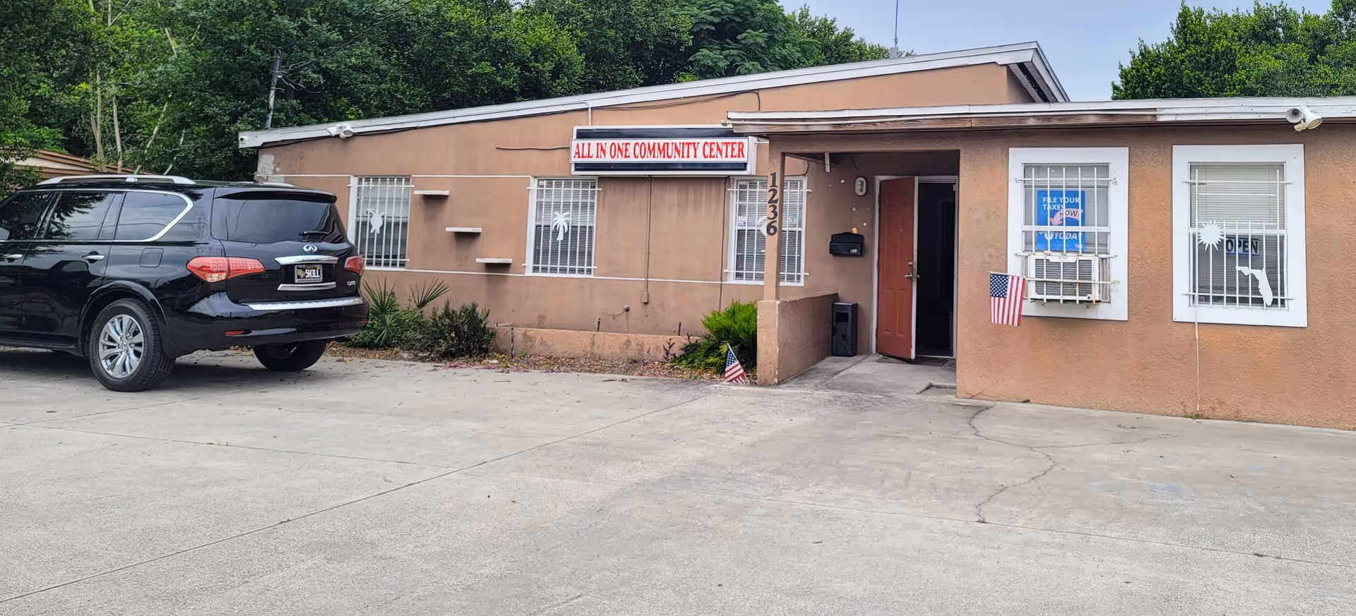 Exterior view of a one-story facility with a sign, entrance, and parked SUV.