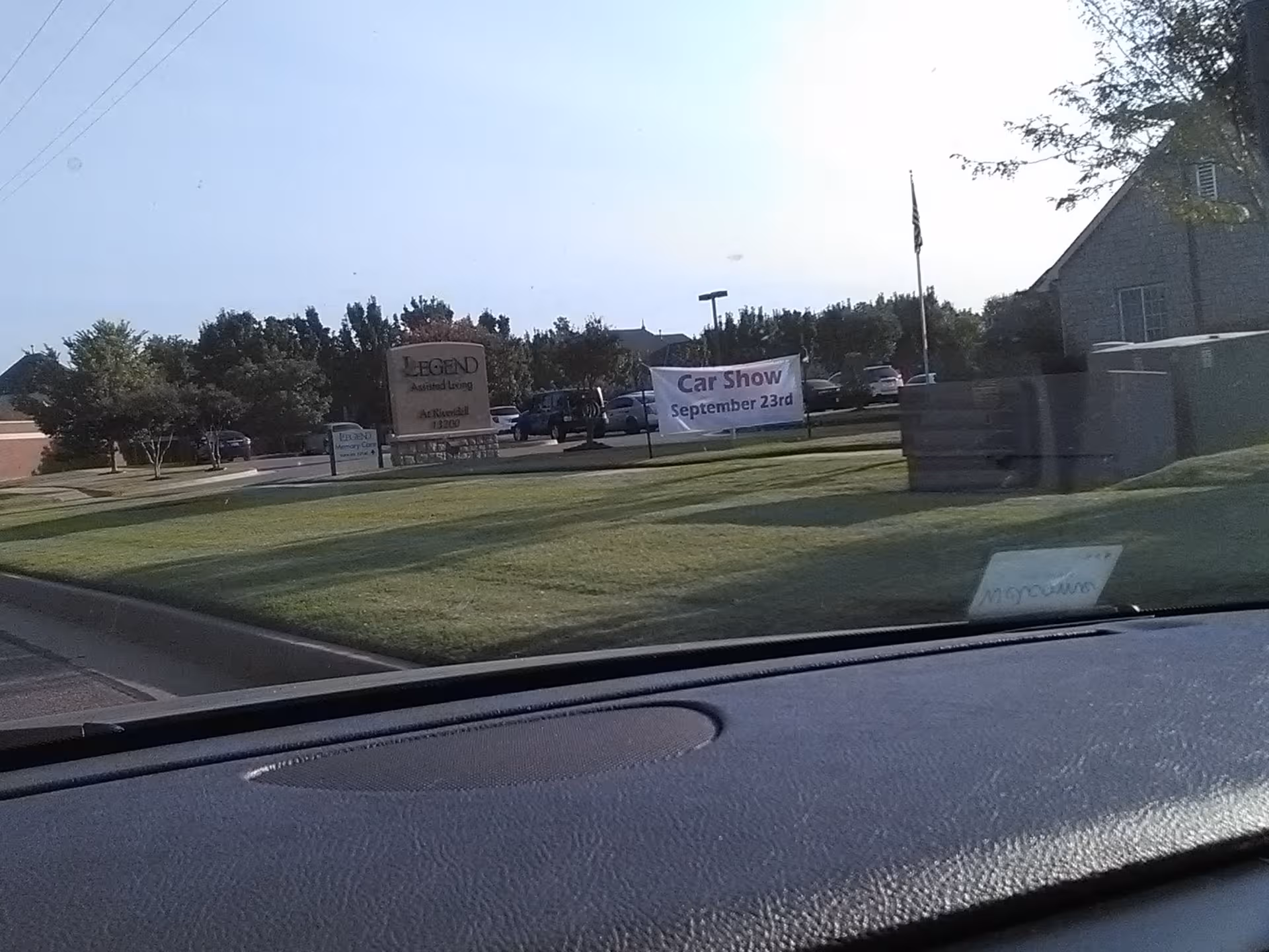 Exterior view of Legend Assisted Living entrance with banners in a parking lot.