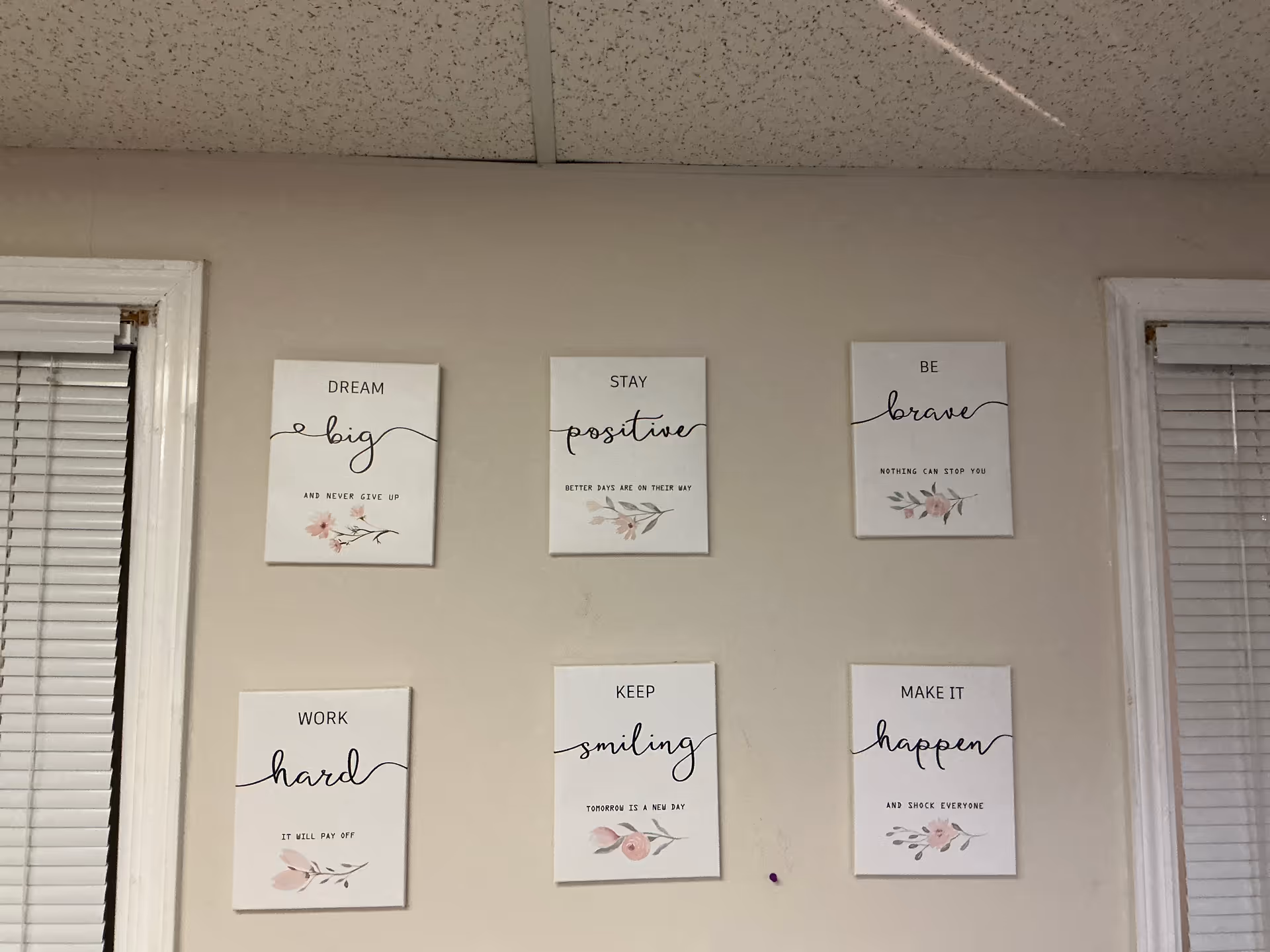 Interior wall displaying six motivational prints with floral accents.