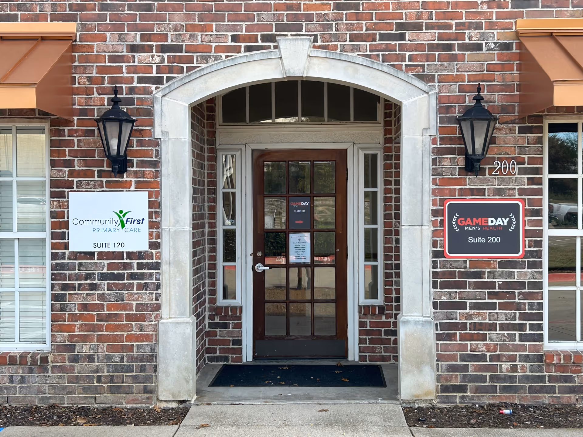 Brick building entrance with arched doorway and signs for Community First Primary Care
