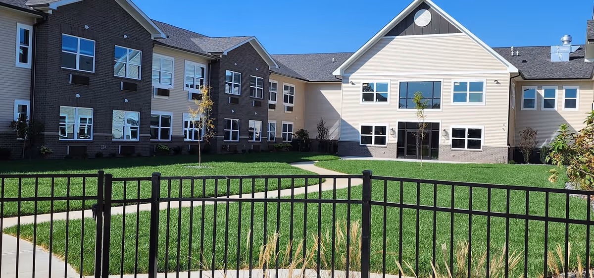 Front view of Autumn Trace Connersville Assisted Living building with green lawn and black fence.