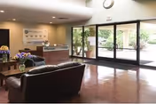 A modern senior living lobby with leather seating, a reception desk, and glass doors.