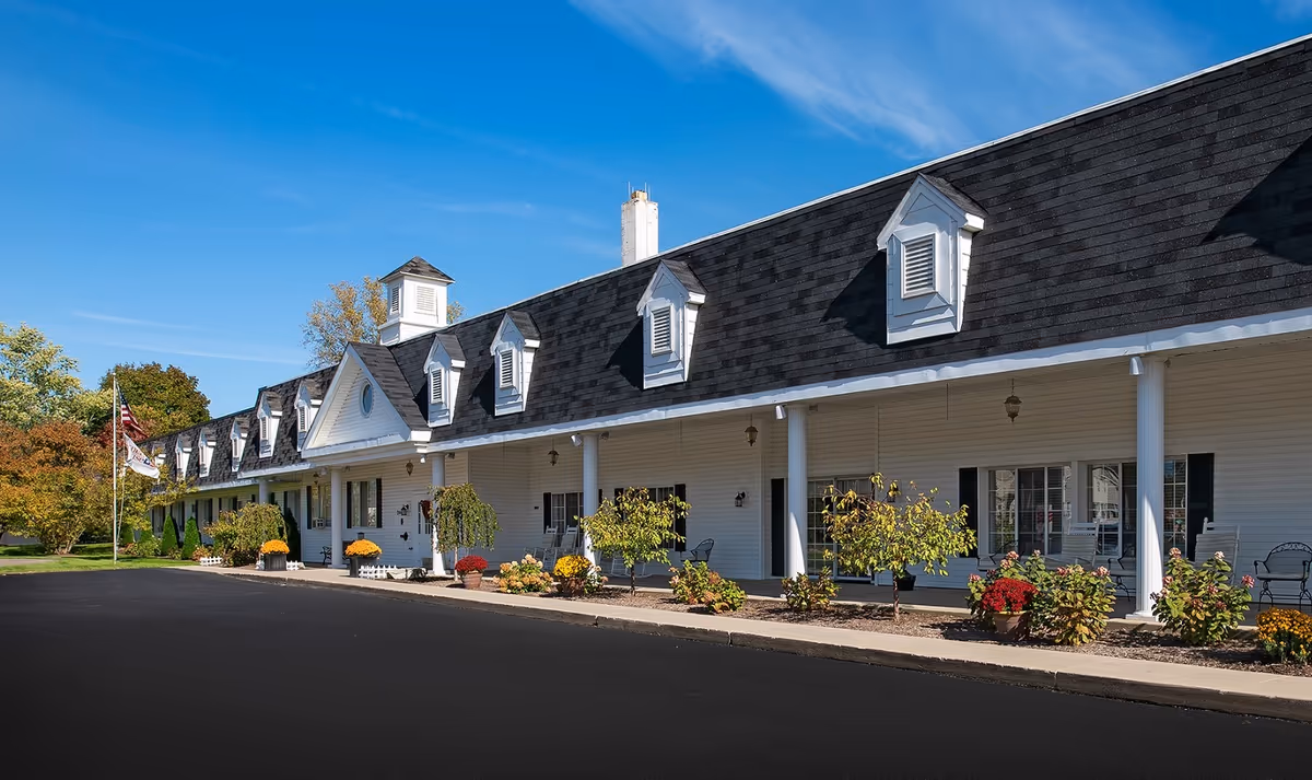 White single-story senior living facility with dormer windows and a manicured front garden.