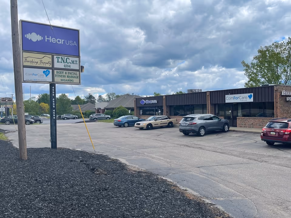 A parking lot in front of a strip plaza with ComForCare storefront signs.