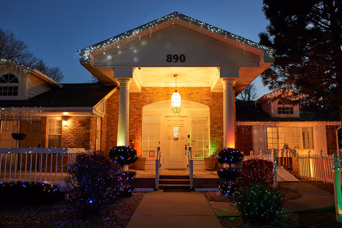 Front entrance of a senior living facility decorated with string lights.