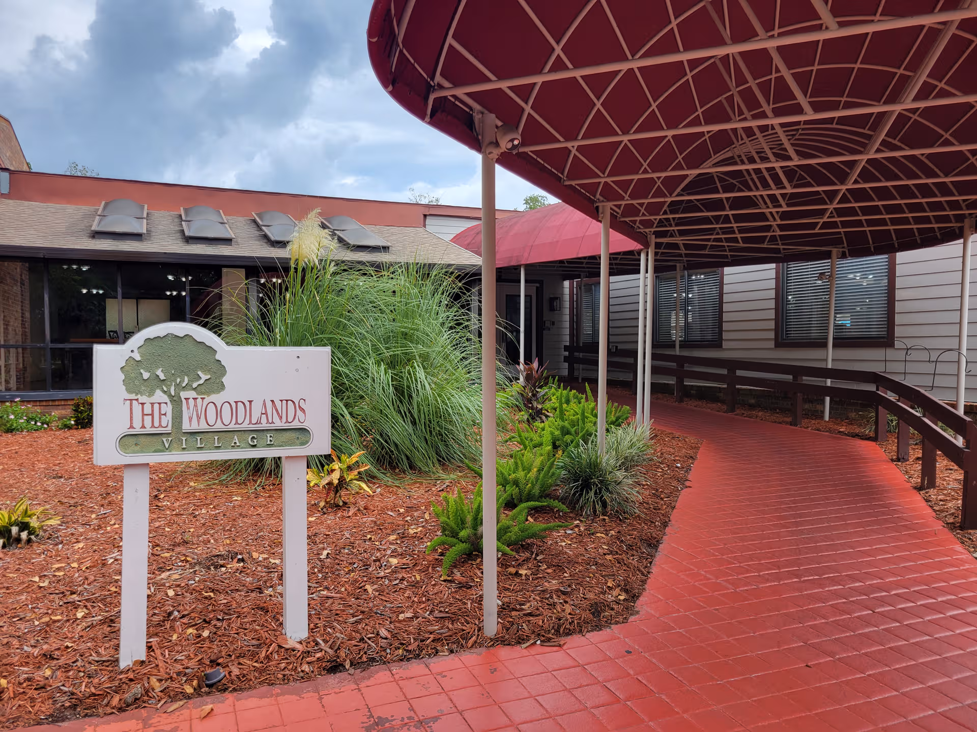 Exterior view of The Woodlands Village Senior Living Community entrance with sign