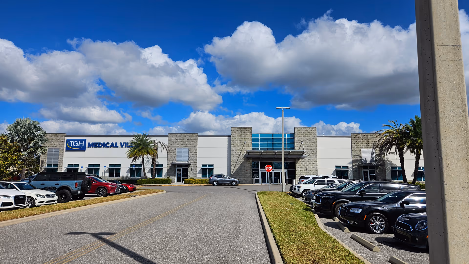 Front view of a medical center building with a parking lot and blue sky.