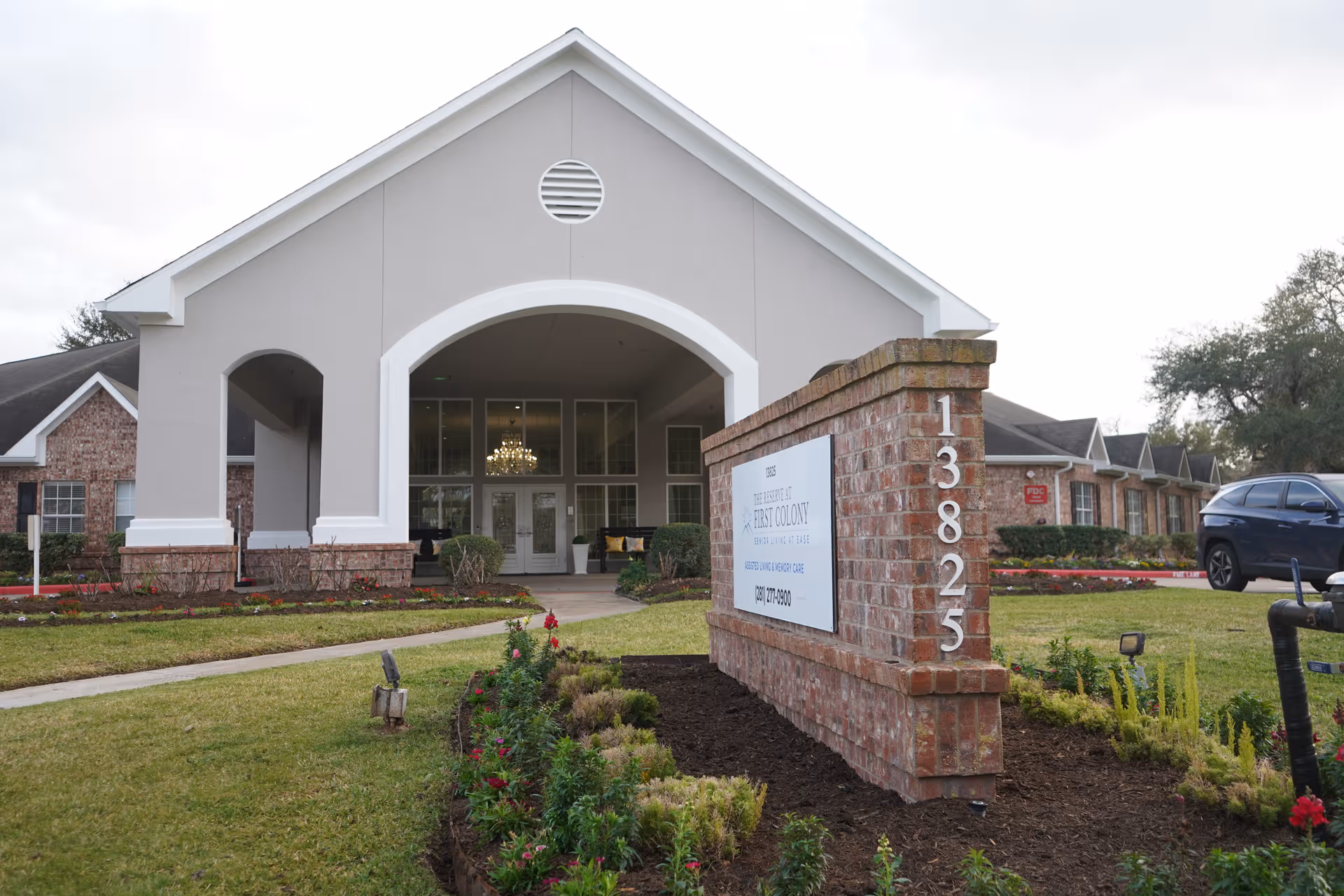 Exterior view of The Reserve at First Colony entrance with an arched portico and brick sign.