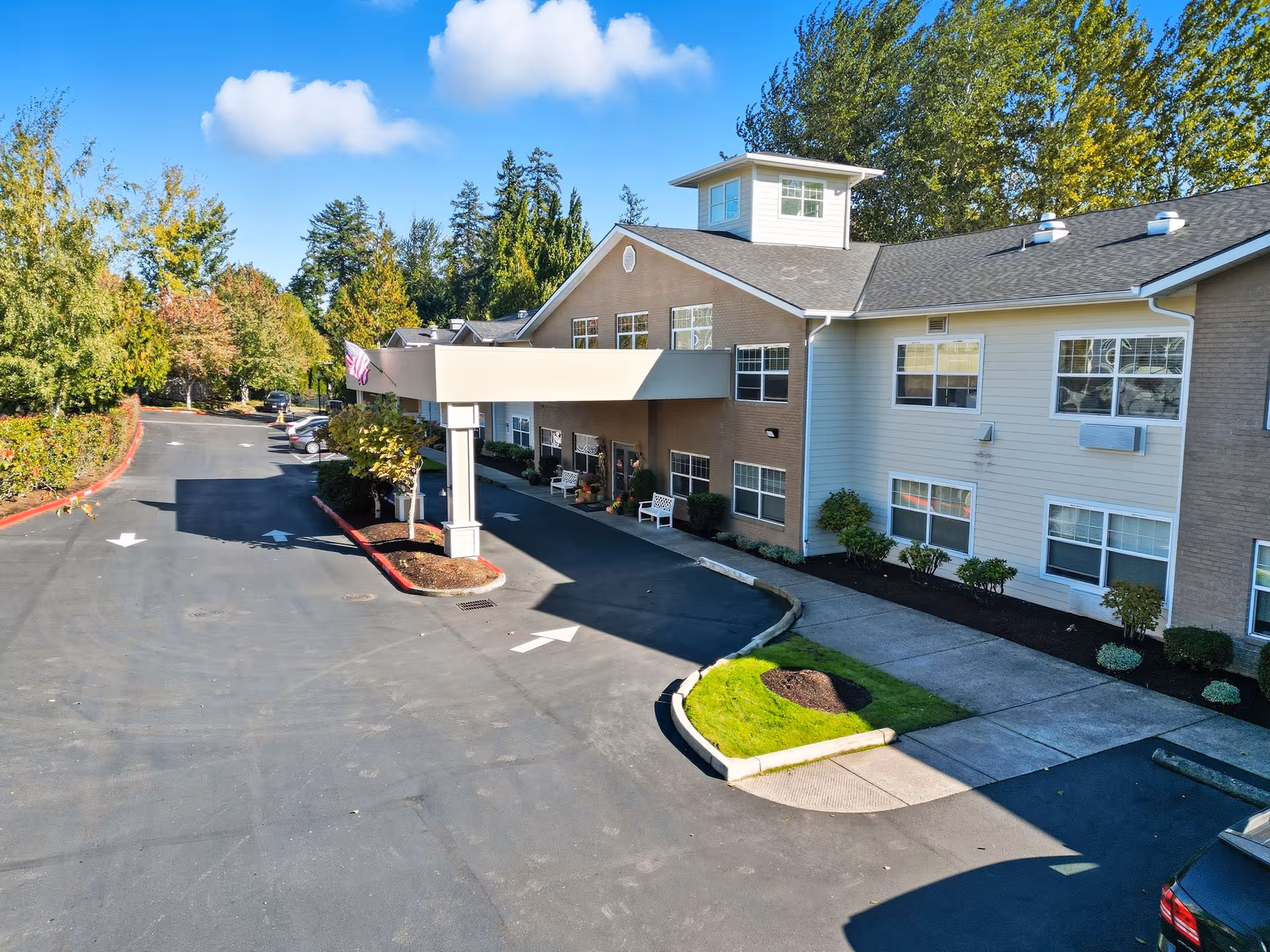 Exterior view of a senior living facility with a curved driveway and landscaped entrance.