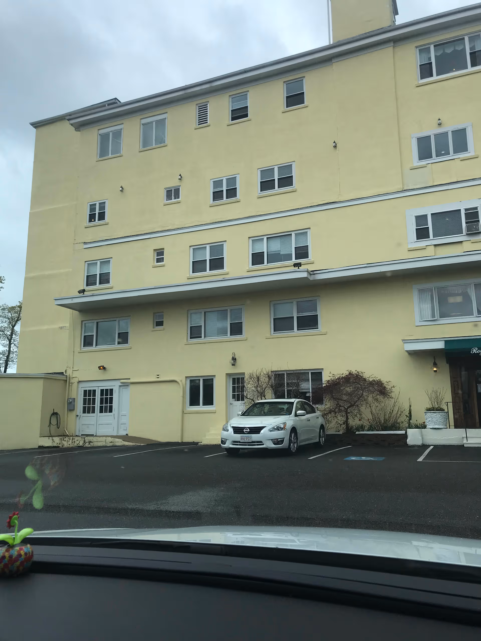 Exterior view of a yellow multi-story nursing home with a parking lot and entrance.