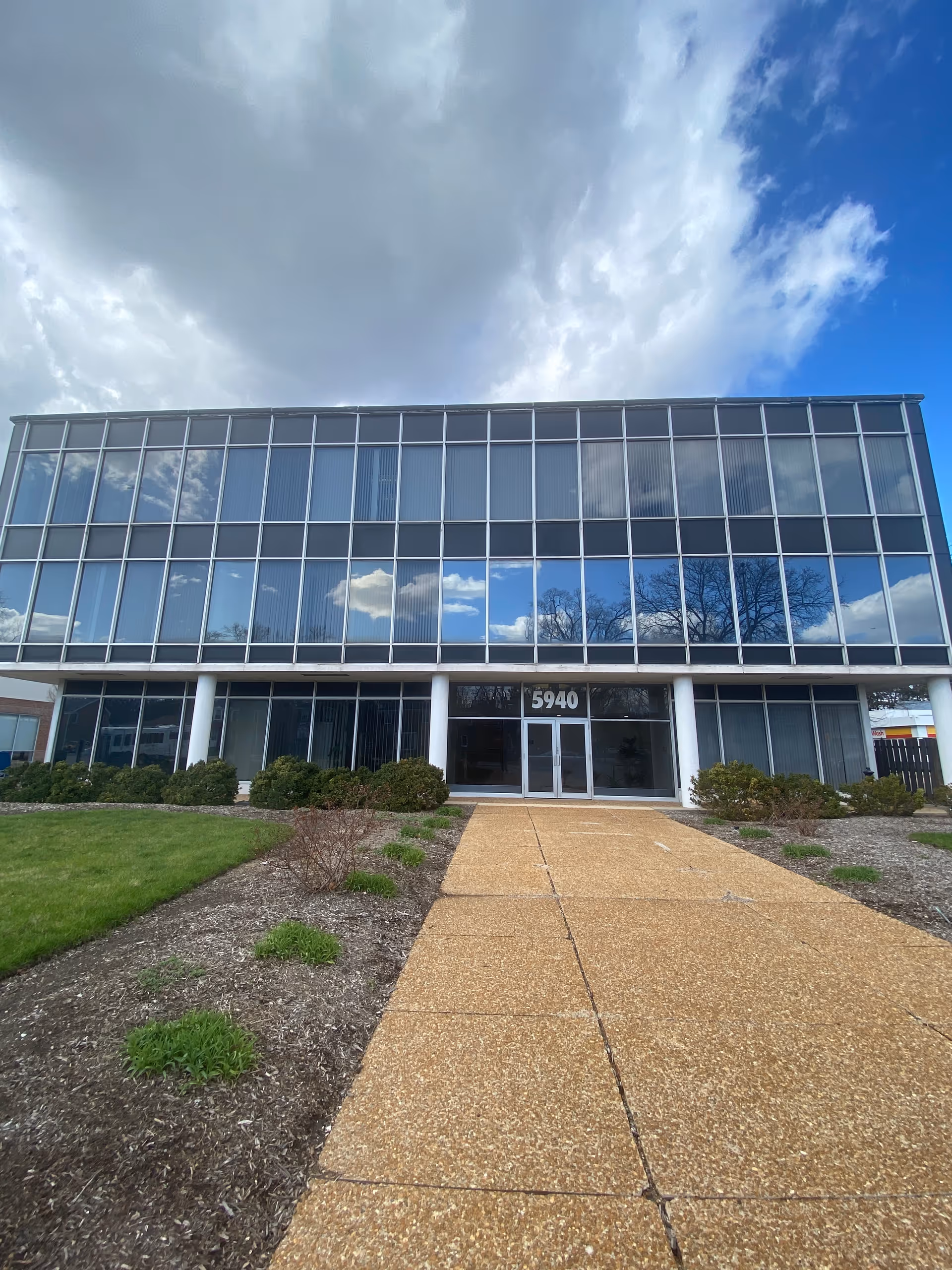Glass-front senior living facility exterior with a walkway to the entrance.