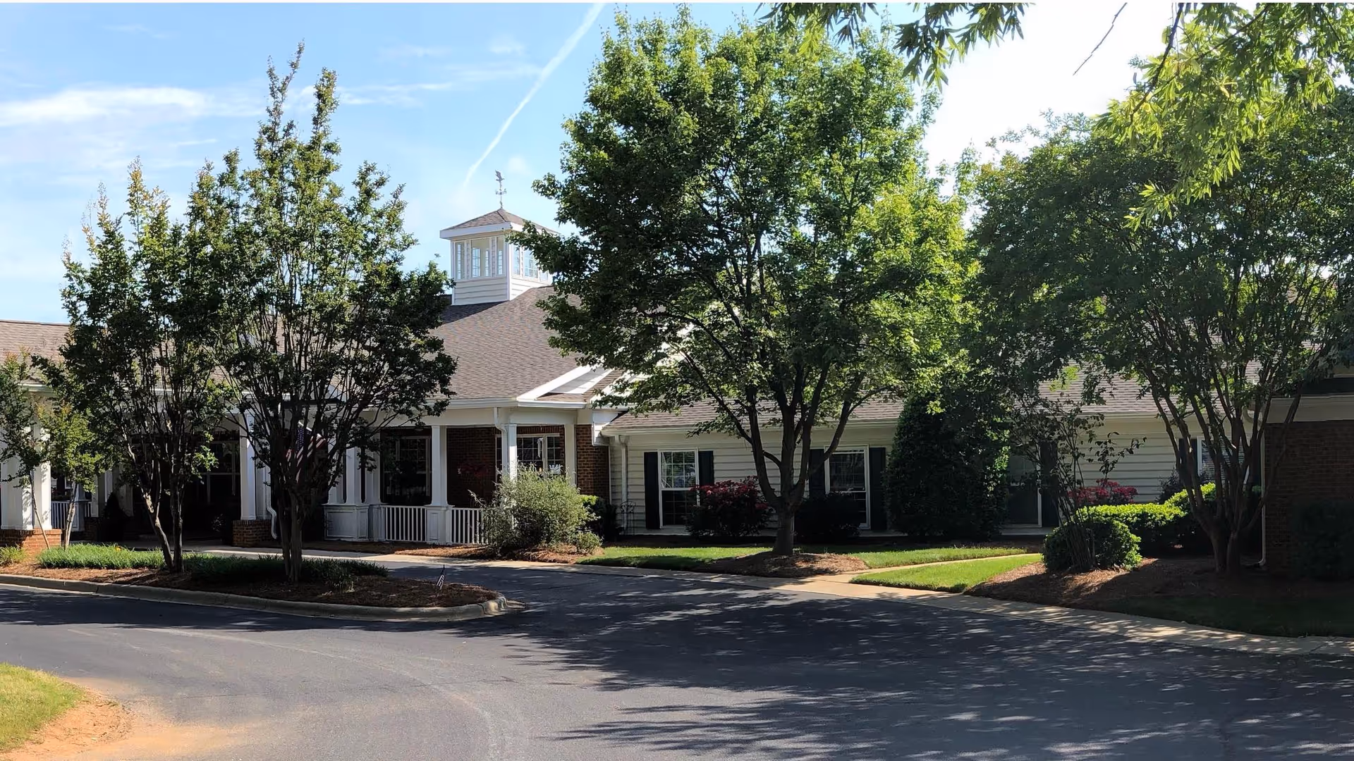 Exterior view of Chandler Place Assisted Living and Memory Care, with entrance, driveway, and trees.