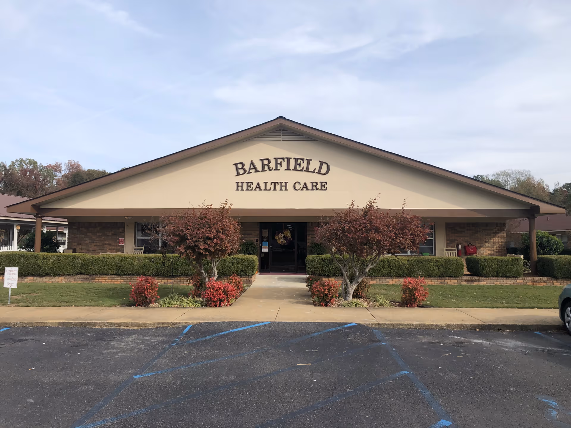 Front view of Barfield Health Care facility with entrance and landscaped shrubs.