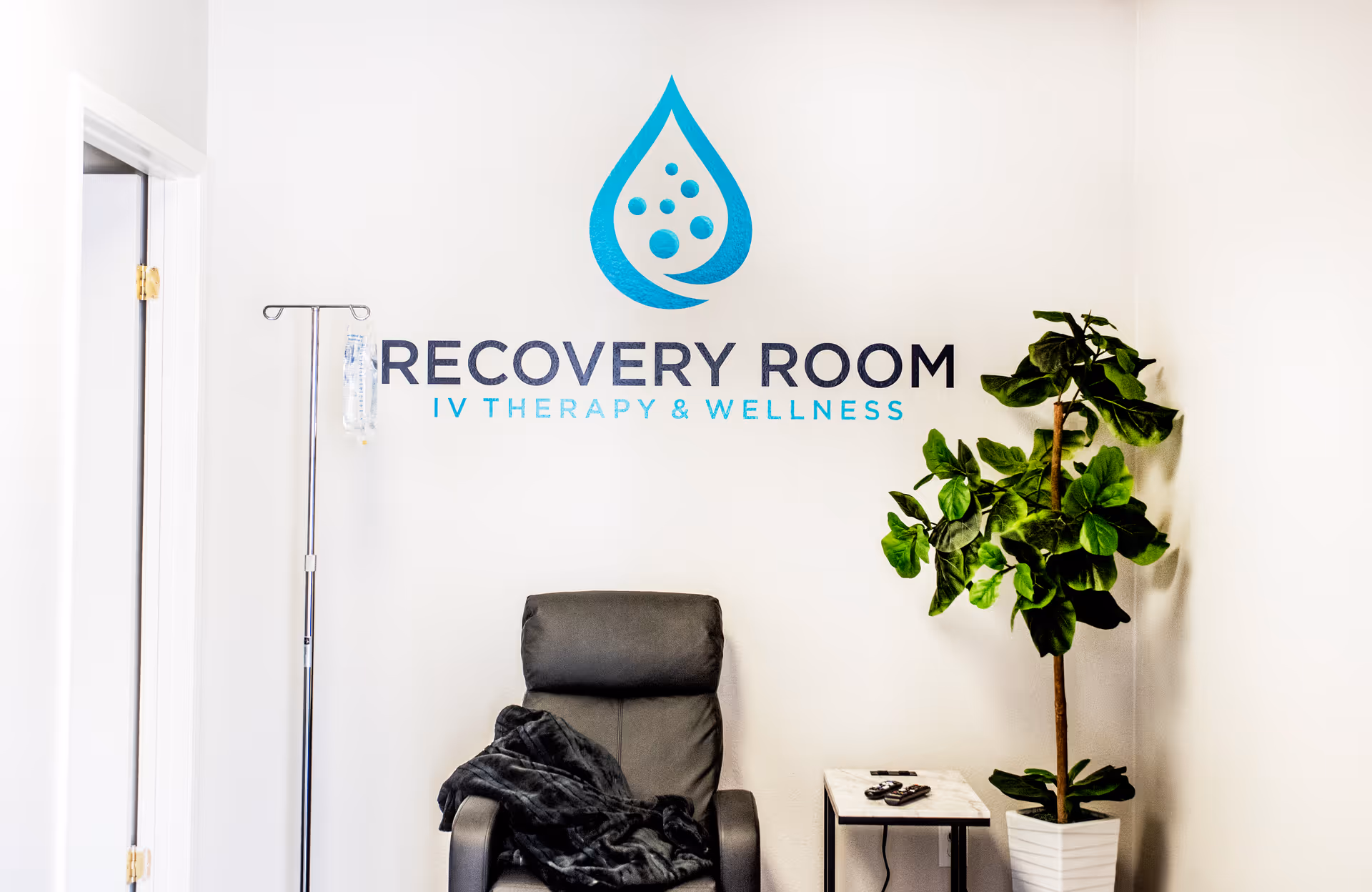 Recovery Room IV Therapy & Wellness sign on wall with chair and plant