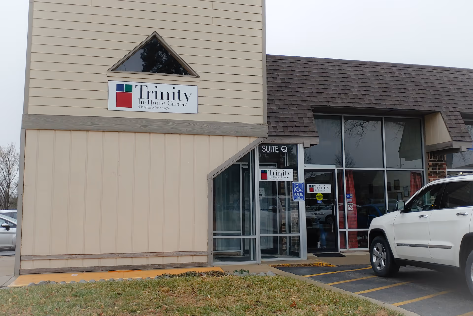 Exterior view of Trinity In-Home Care building with glass entry and parked white SUV.
