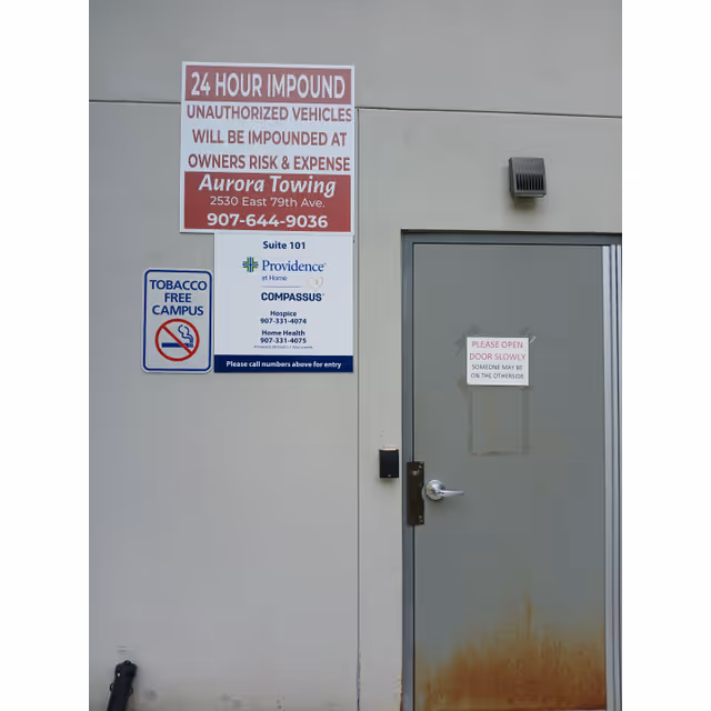 Exterior wall with multiple signs and a gray door at Providence at Home with Compassus.