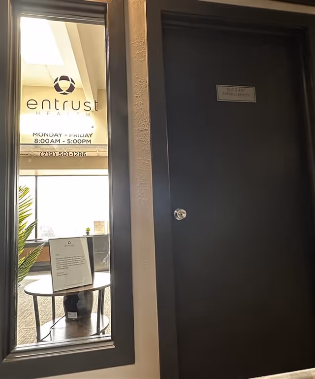 Interior entrance area with glass window displaying Entrust Health sign and a dark door.