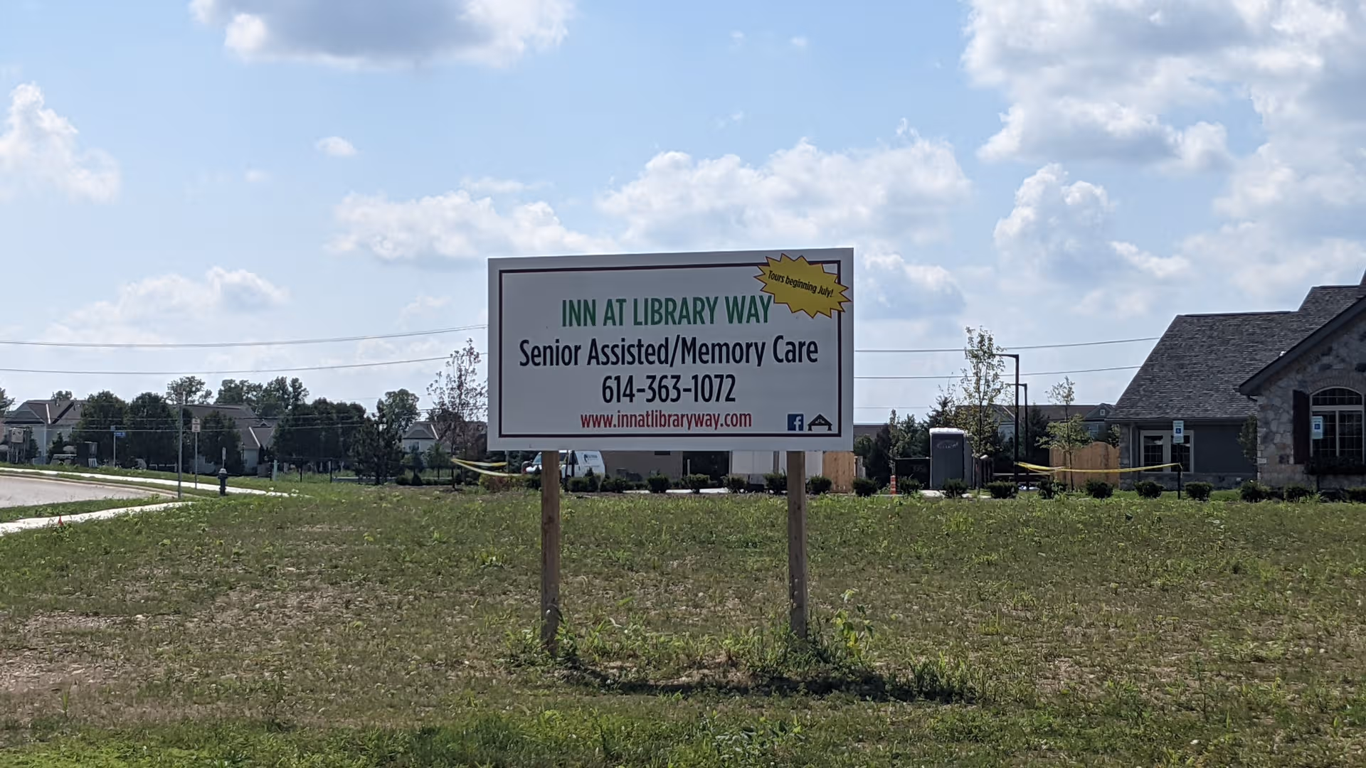Signboard for Inn at Library Way in front of a building on grass.