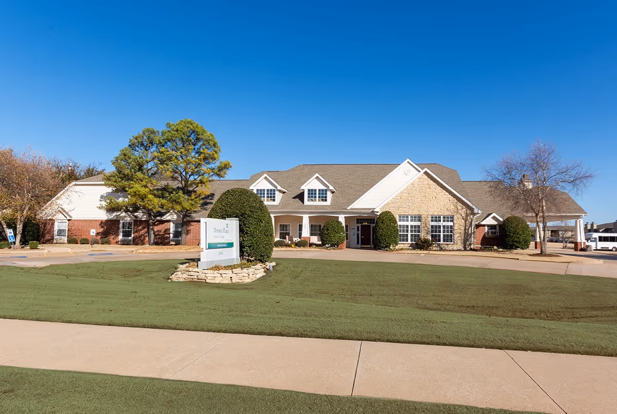 A single-story assisted living building with a landscaped lawn, central entrance and a sign reading Dorset Place near the driveway.