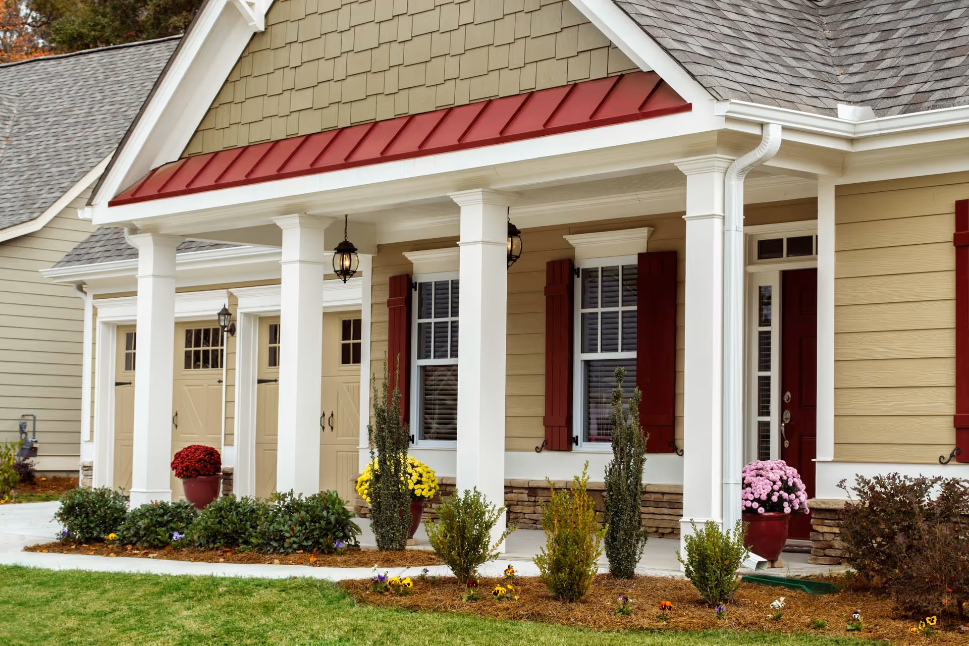 A beige Windsong Manor building with a covered front porch and flower planters.