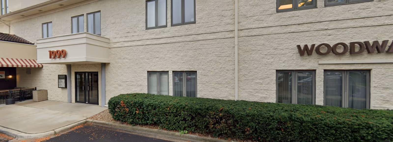 Exterior view of Abcor Home Health Woodridge facility entrance with hedges and a sidewalk.