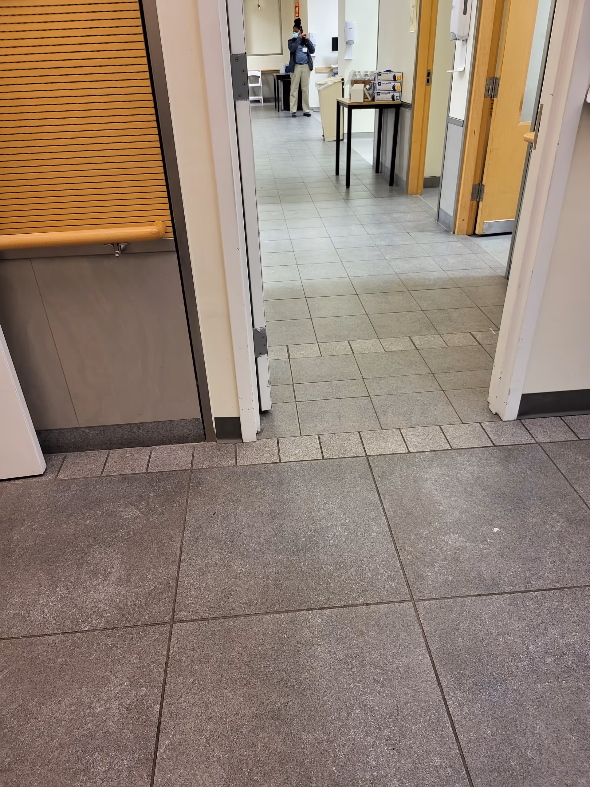 Indoor hospital corridor at Martha Stewart Center for Living, featuring tiled floor and open doorways.