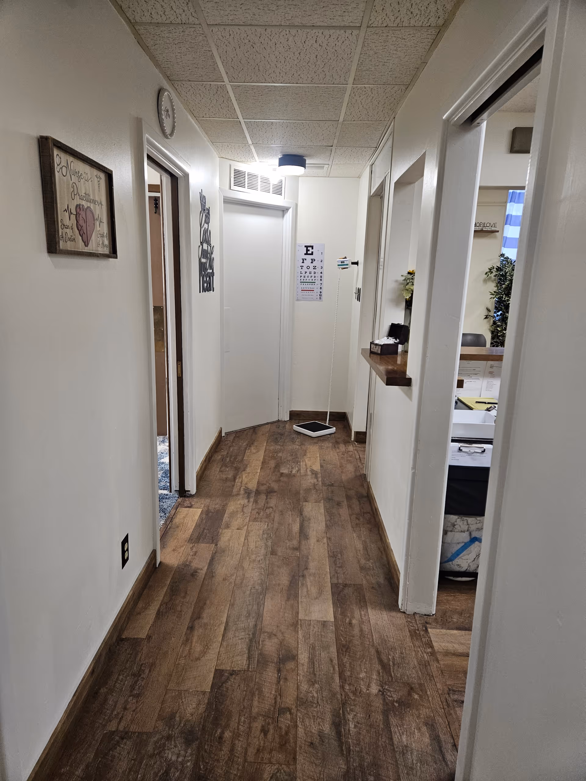 Indoor hallway in a senior care facility with doors, wood-like flooring, and decor.