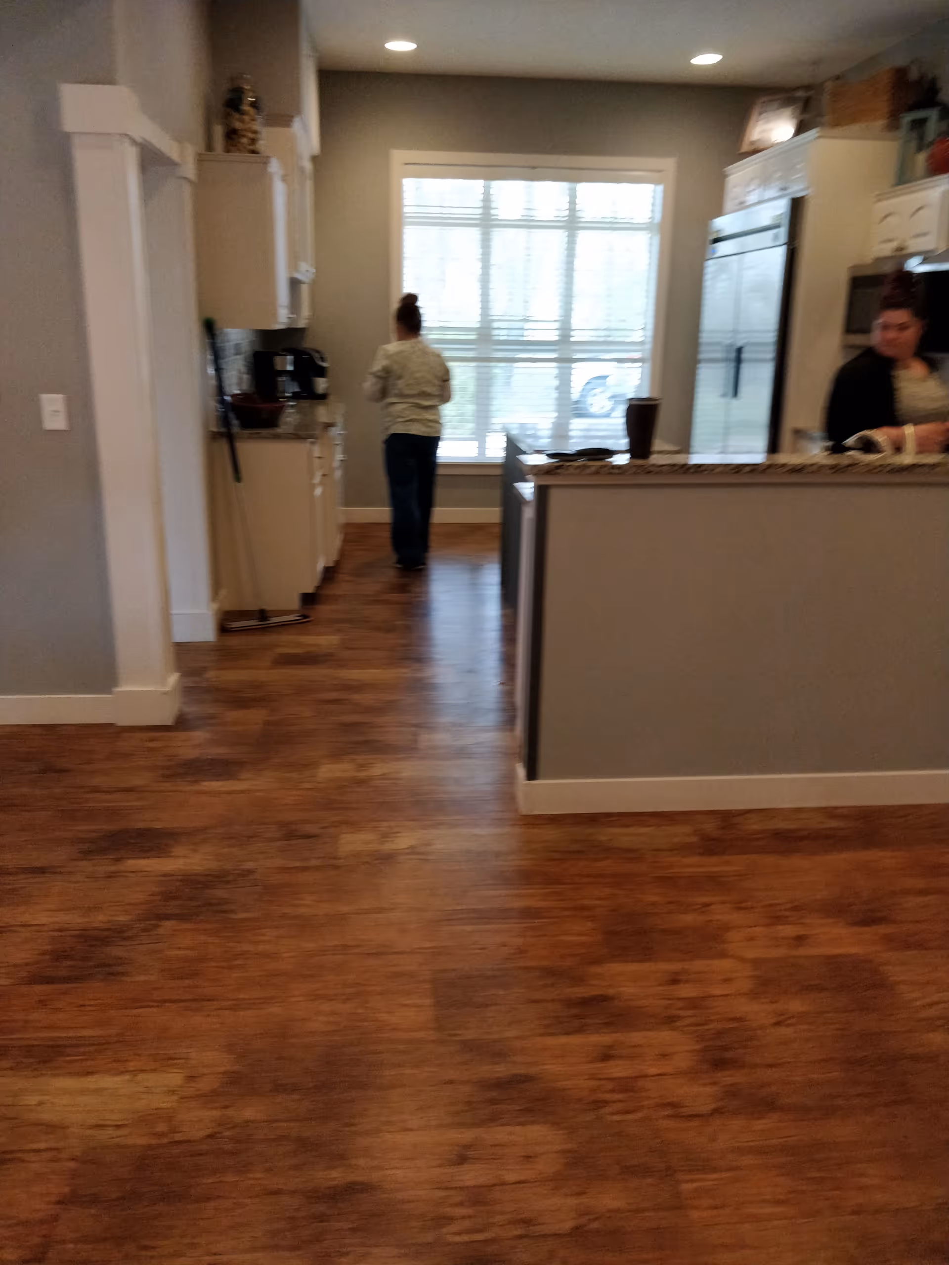 Two people stand near a kitchen island in a senior living facility.