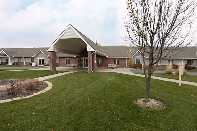 Exterior view of a senior living facility with brick building and covered entrance.