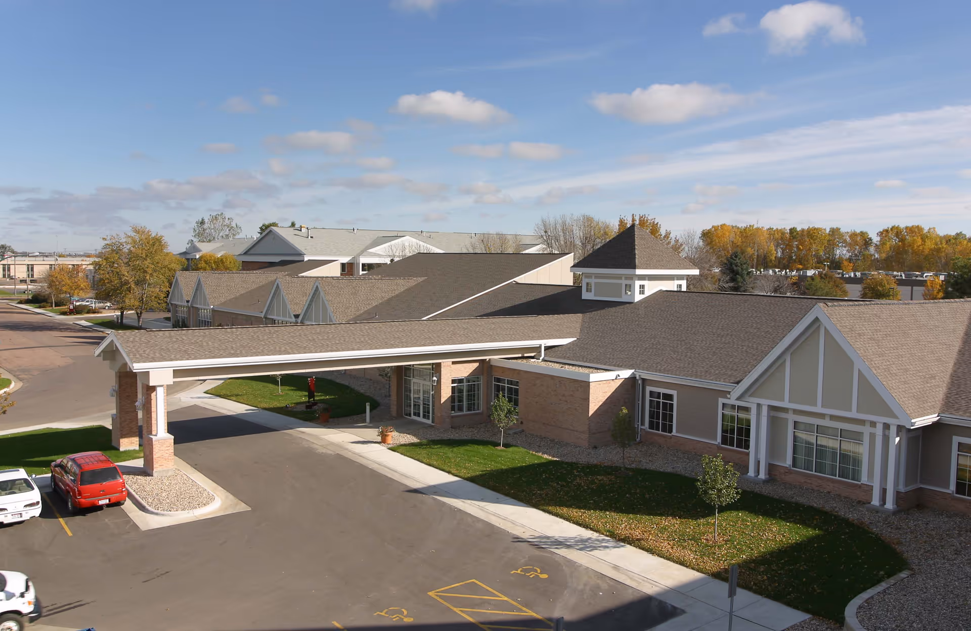 A senior living facility exterior with a covered entrance and parking lot.