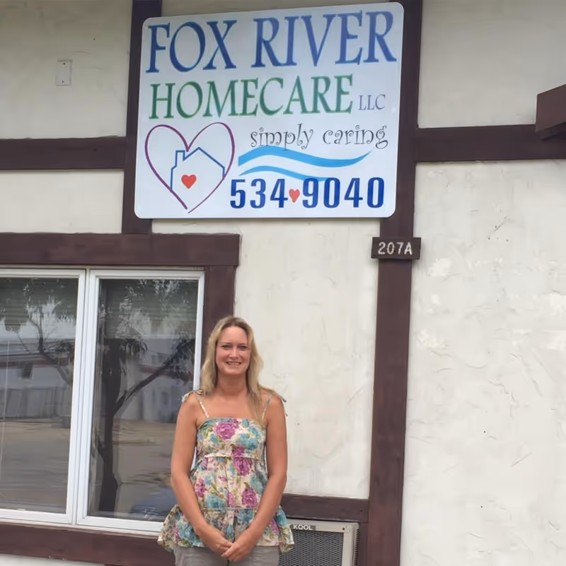 Woman stands in front of Fox River Home Care LLC building exterior with signage.