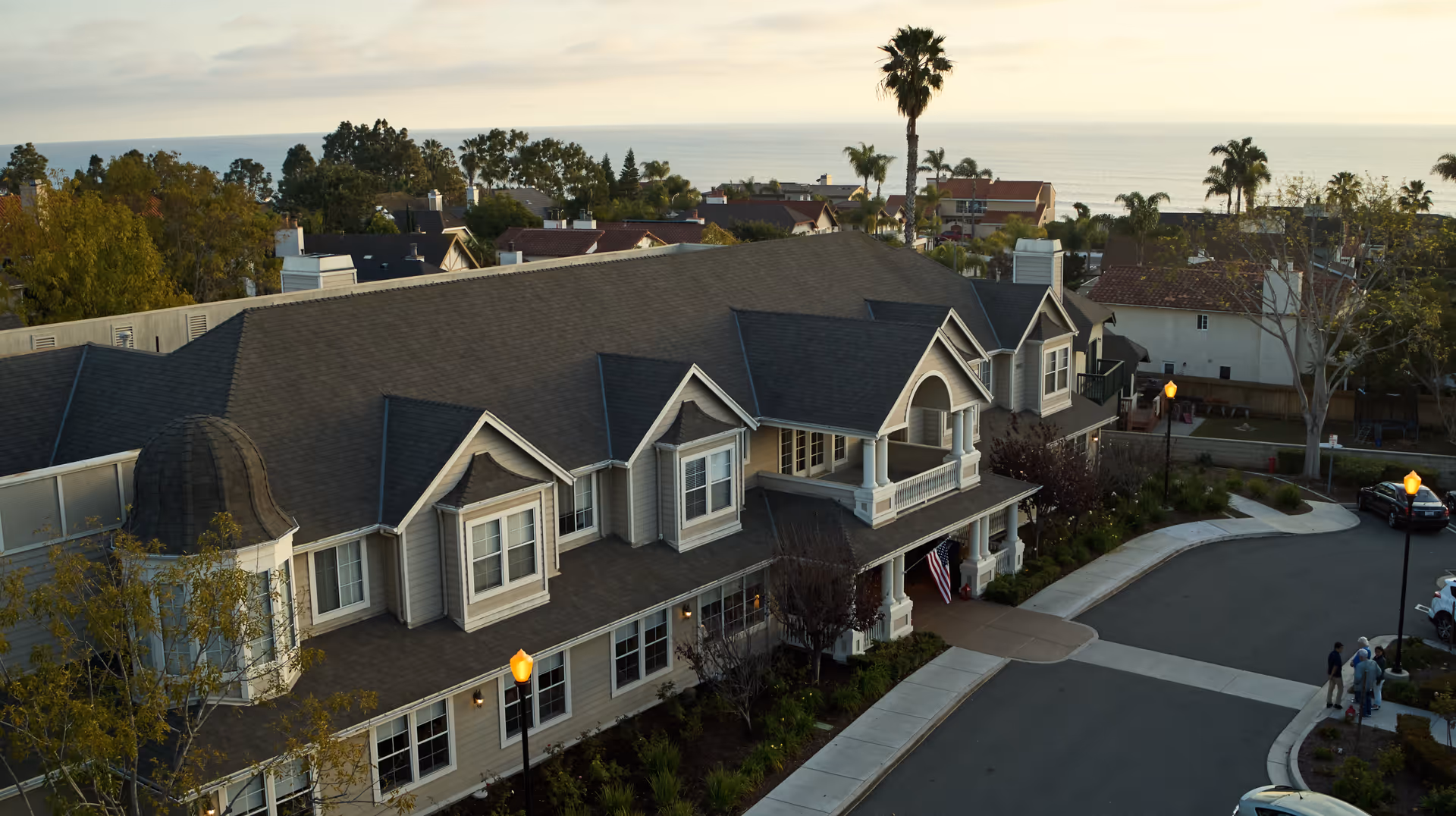 Aegis Living Dana Point building exterior with curved driveway and ocean backdrop.