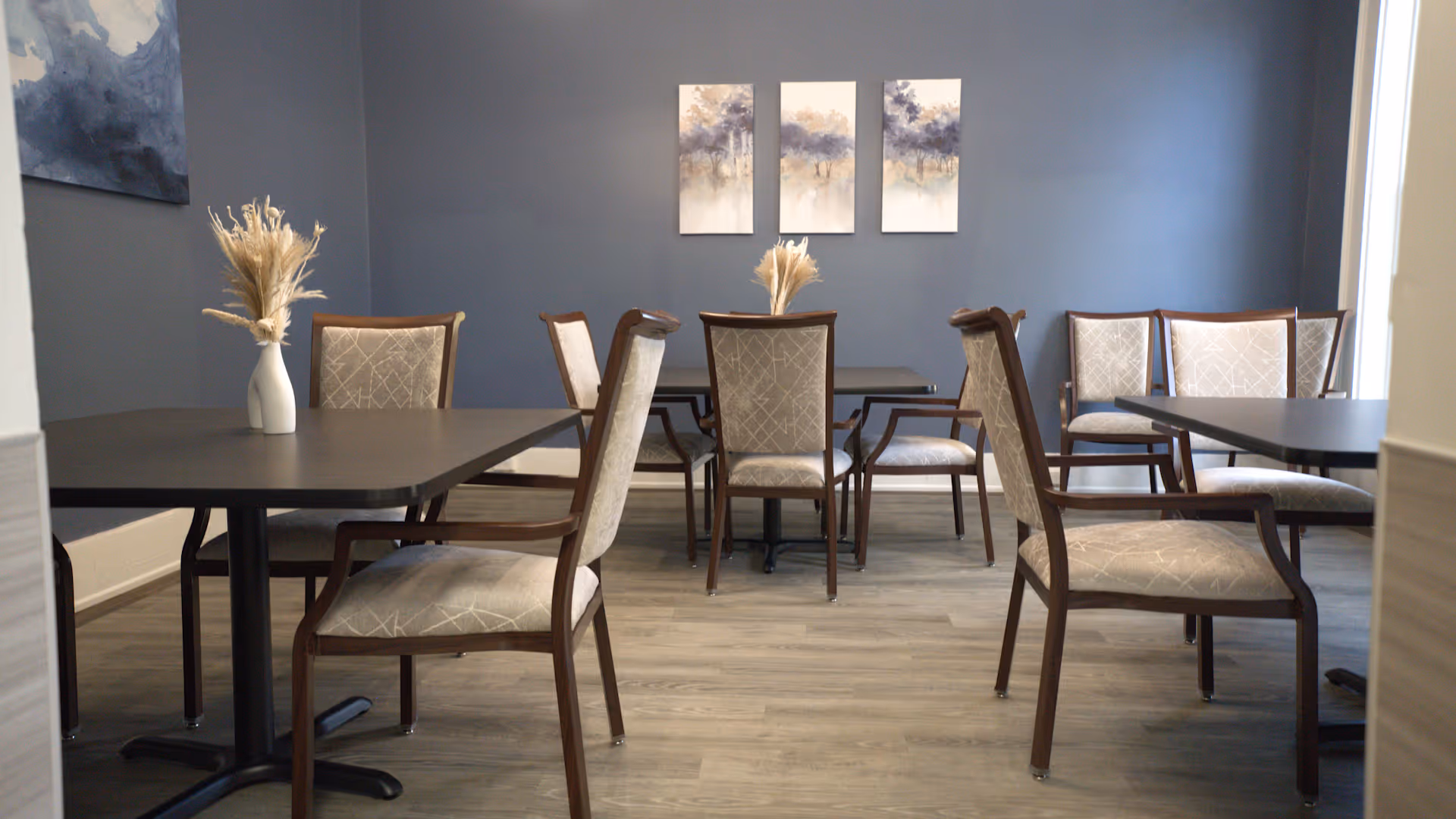 Blue dining room with dark tables and upholstered patterned chairs.