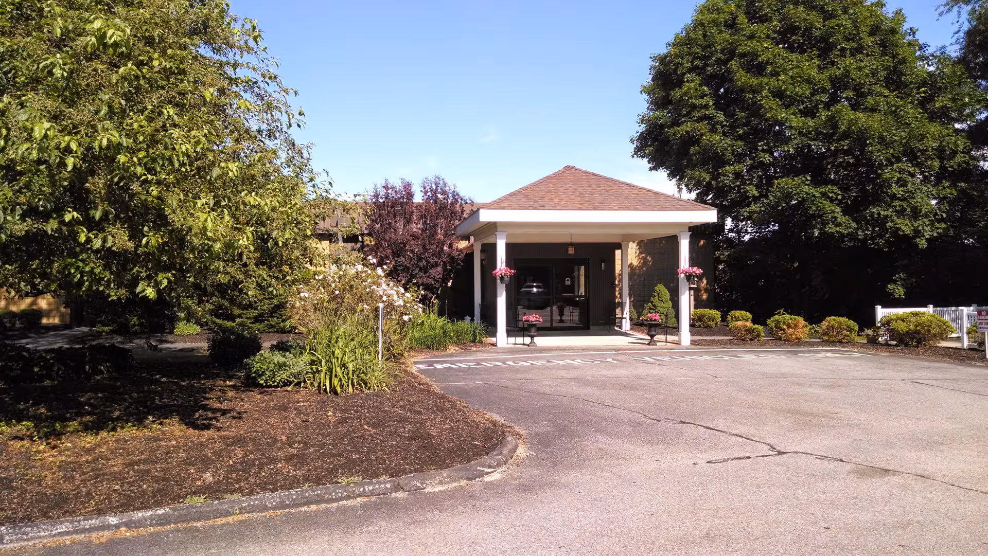 Front entrance of Life Care Center Scituate with trees, parking lot, and a covered entry.