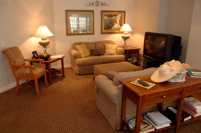 Cozy living room at Covenant Shores Health Center with sofa, chairs, lamps, and a TV.