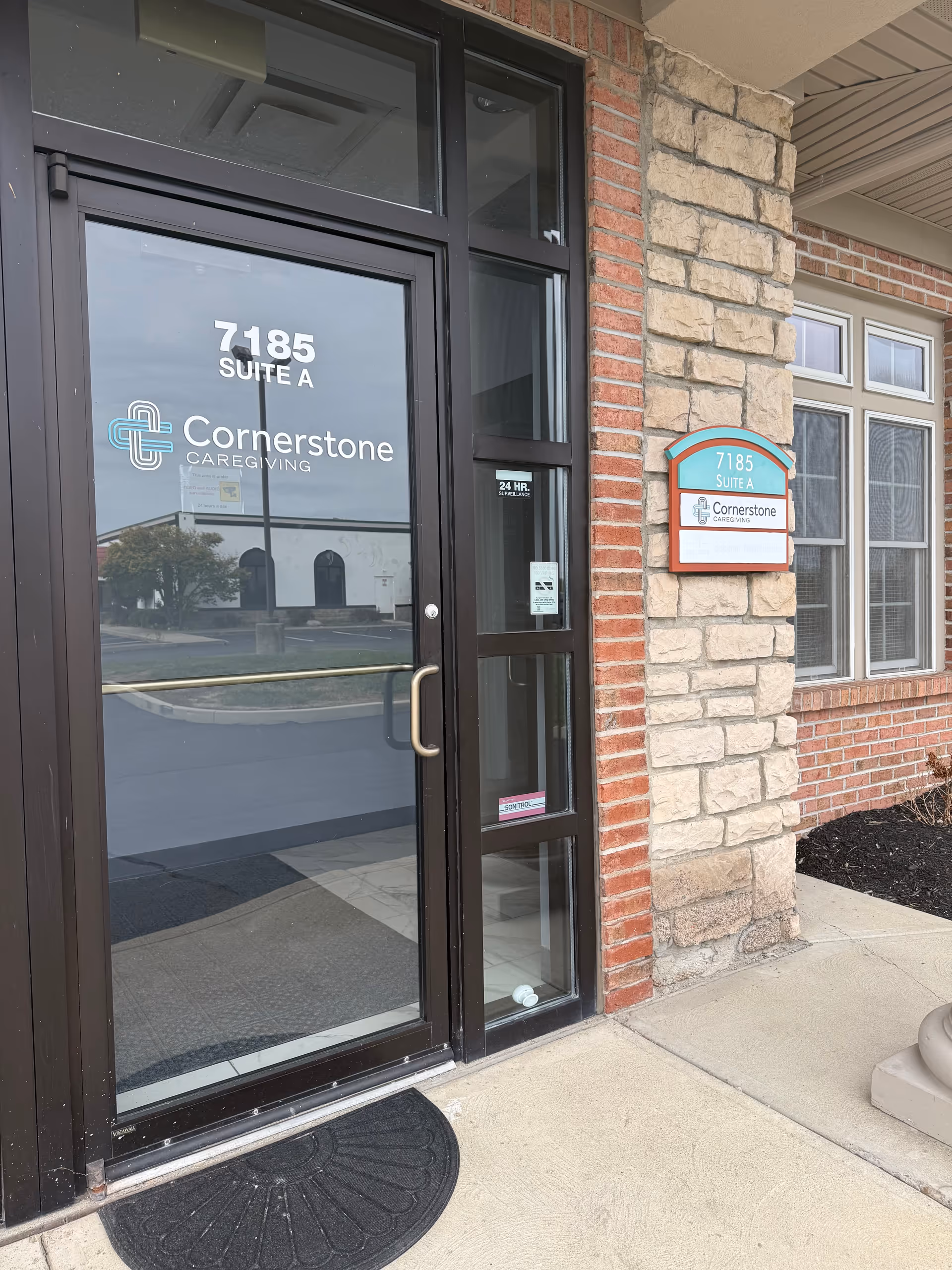 Exterior view of Cornerstone Caregiving entrance with glass door and address plaque.