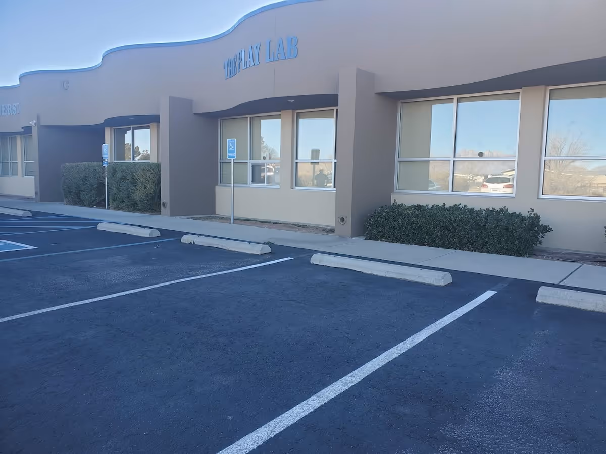 Exterior view of The Play Lab facility with parking lot and front windows.