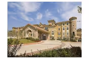 Exterior view of Evergreen at Plano senior living facility with arched entrance and turret