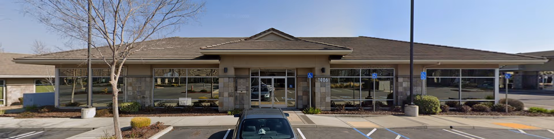 Exterior view of a single-story senior care facility with parking in front.