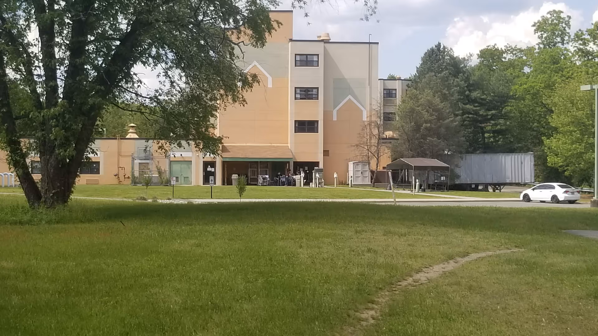 Front view of a multi-story senior facility surrounded by green lawn and trees