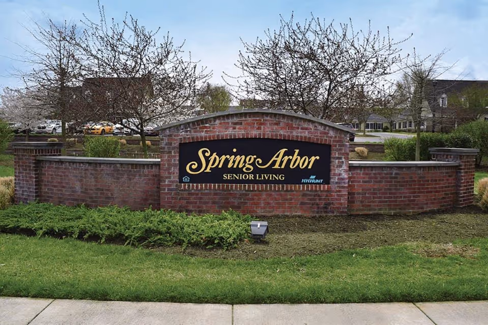 Exterior brick sign reads Spring Arbor Senior Living with surrounding landscaping.