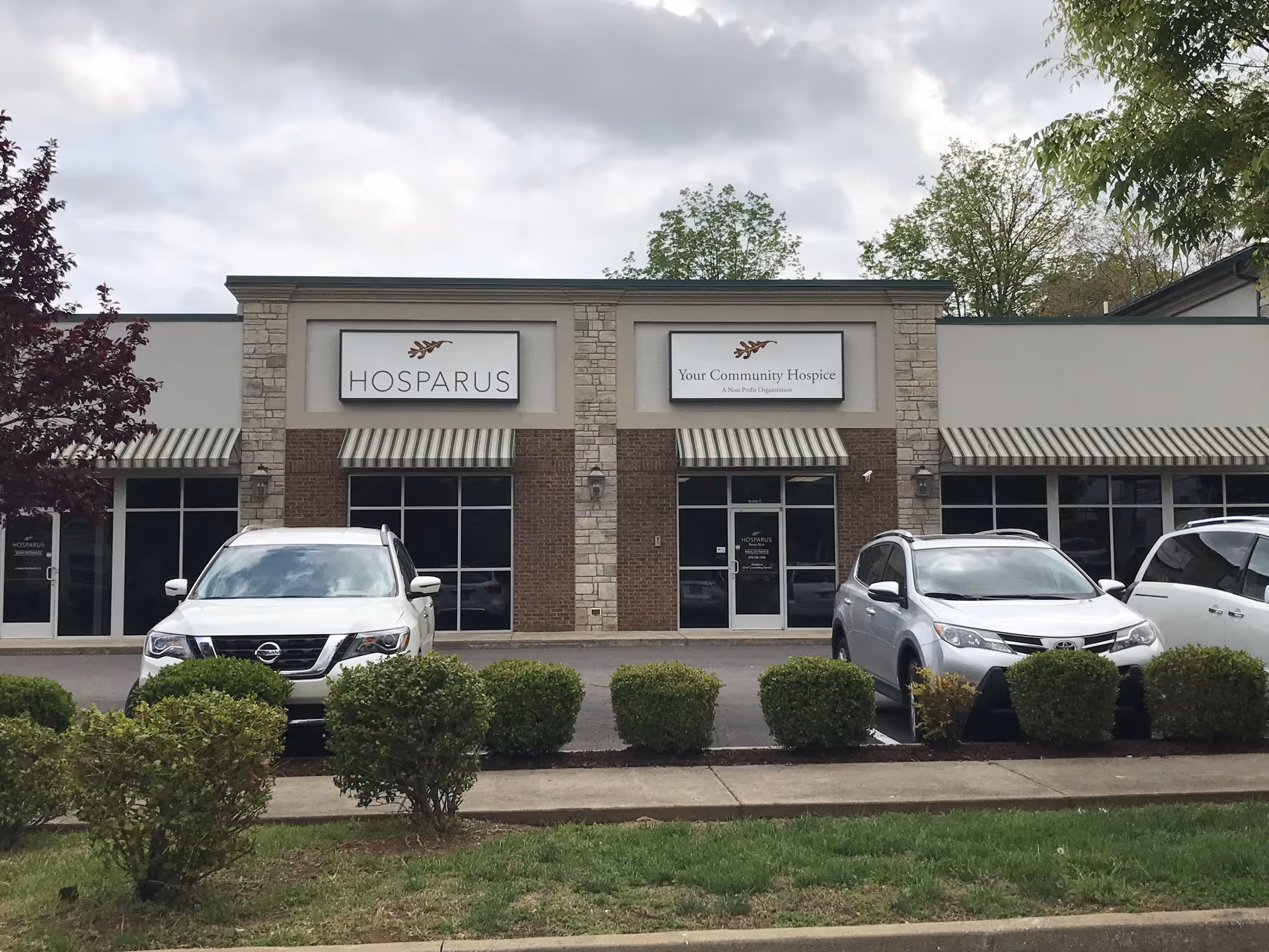 Exterior view of a Hosparus Health building with parked cars.