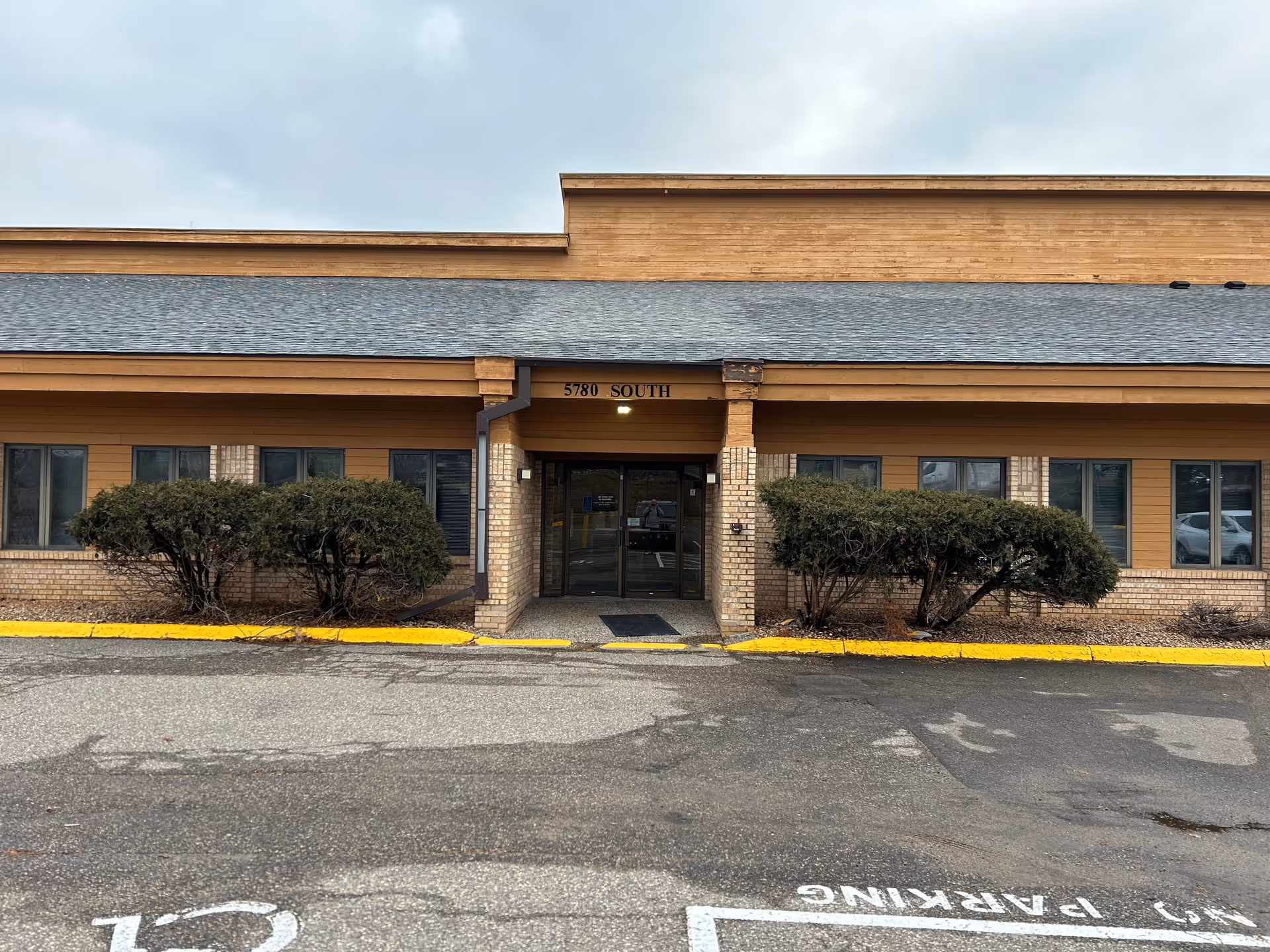 Exterior view of Touching Hearts at Home building with entry and shrubs.