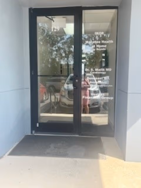 Glass double doors with reflected car outside and facility name on the glass.