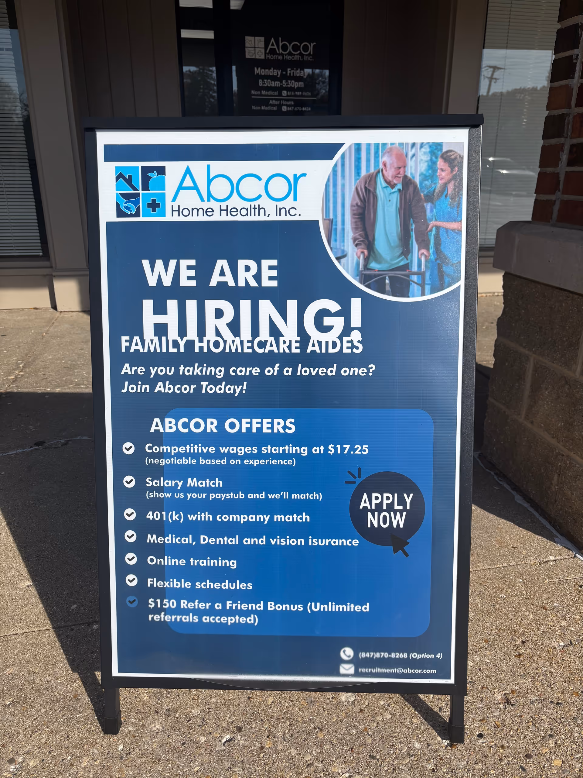 Blue Abcor Home Health hiring sign on a sidewalk outside a building entrance.