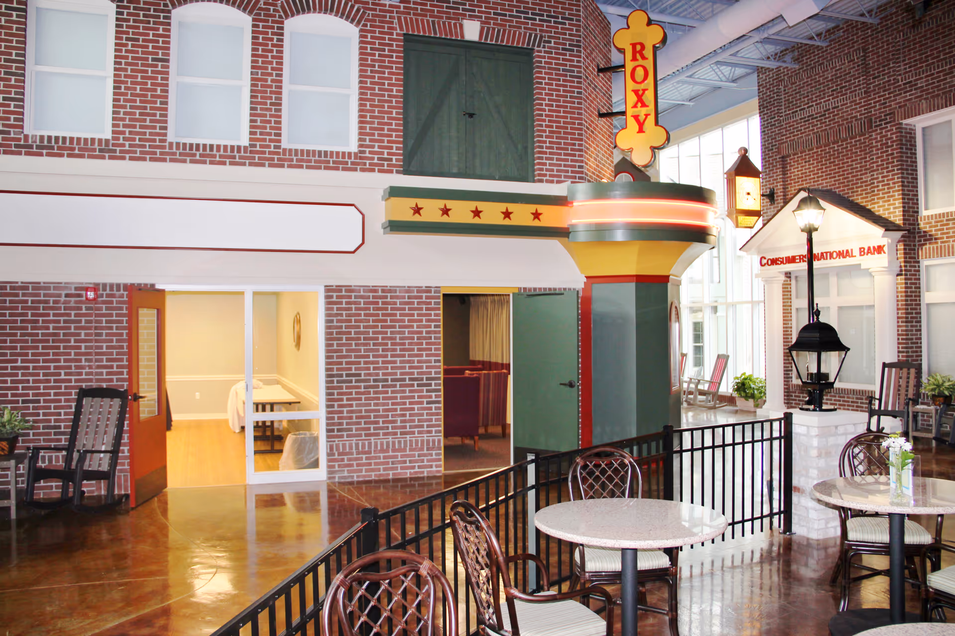 Indoor common area designed like a small-town streetscape with brick storefronts, tables, and a 'ROXY' marquee sign.