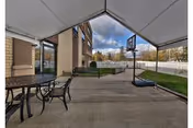 Outdoor covered patio at Achieve Rehab and Nursing Facility with tables, benches, and a basketball hoop.
